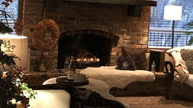 A cozy living room with a stone fireplace, a comfortable sofa, and a large window providing a view of the outdoors.