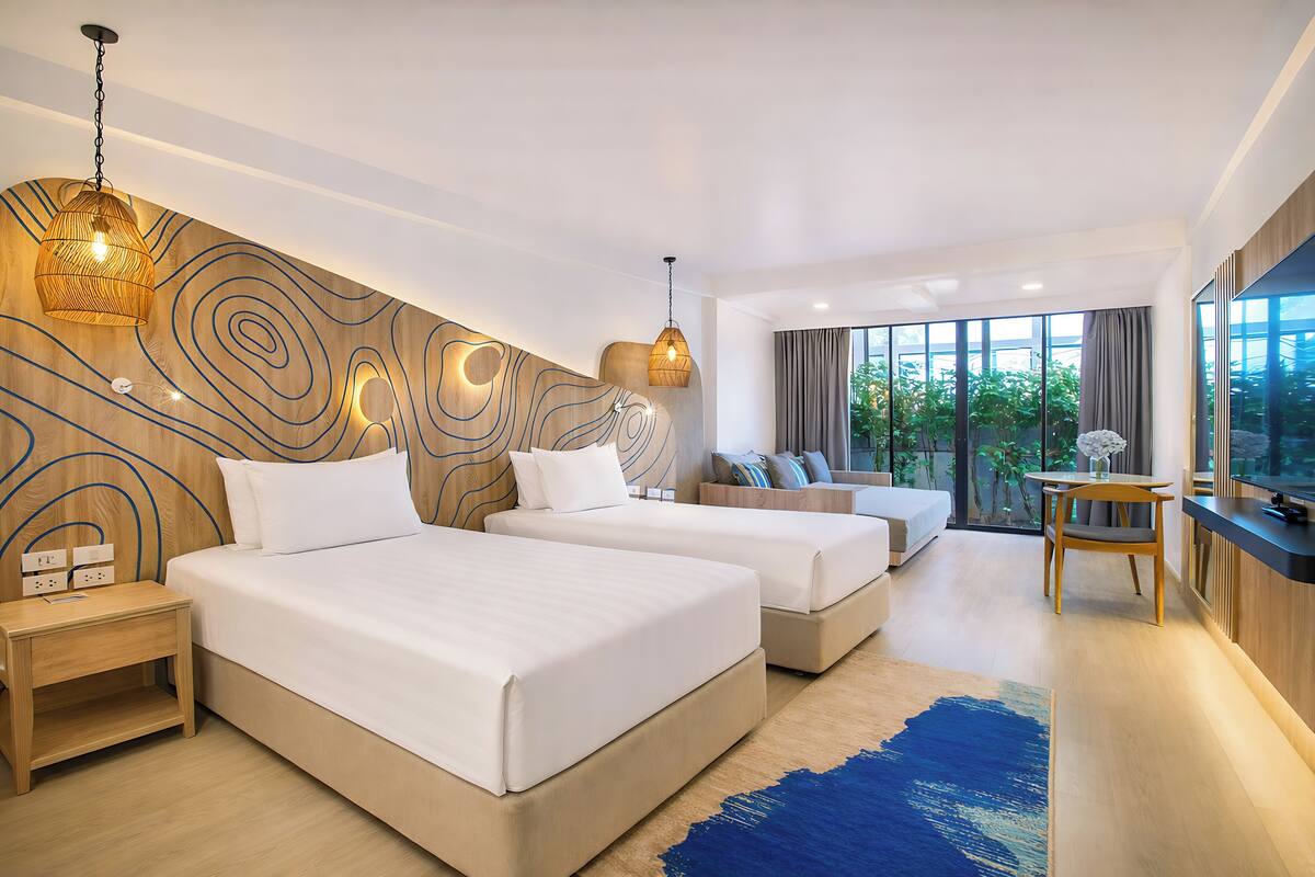 Een moderne hotelkamer met twee bedden, een wand van hout, een zithoek en een groot raam met uitzicht.