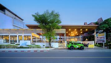 A hotel with a modern design, a green car parked in front, and a sign for the hotel.