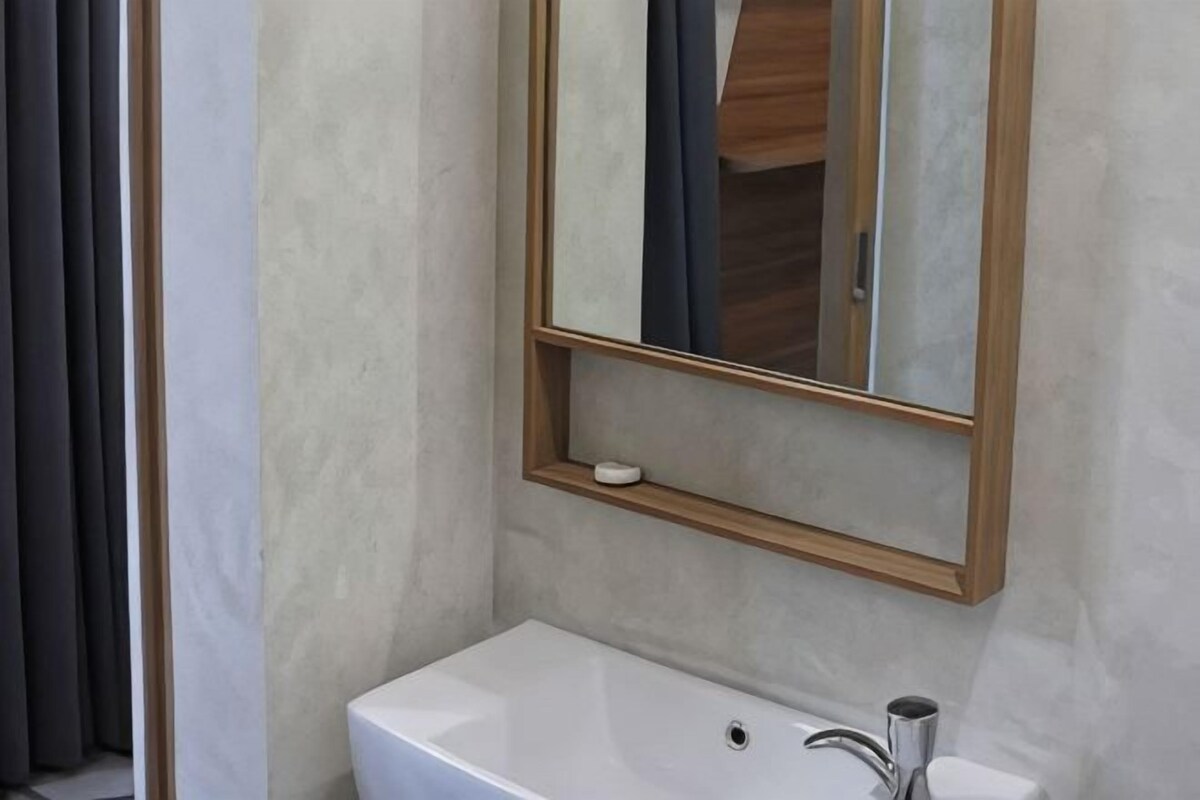 A bathroom with a white sink, a mirror with a wooden frame, and a small shelf with a soap dish.