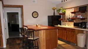 A kitchen with a wooden island, bar stools, a refrigerator, a microwave, and a trash can. - Canyon Lake Texas Hill Country (Canyon Lake)