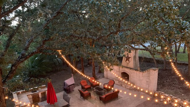 An outdoor patio with stone seating, a fire pit, and string lights. - Canyon Lake Texas Hill Country (Canyon Lake)