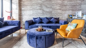 A modern living room with a blue sofa, an orange armchair, and a round ottoman. - Kenting seawall Inn 112 (Hengchun)
