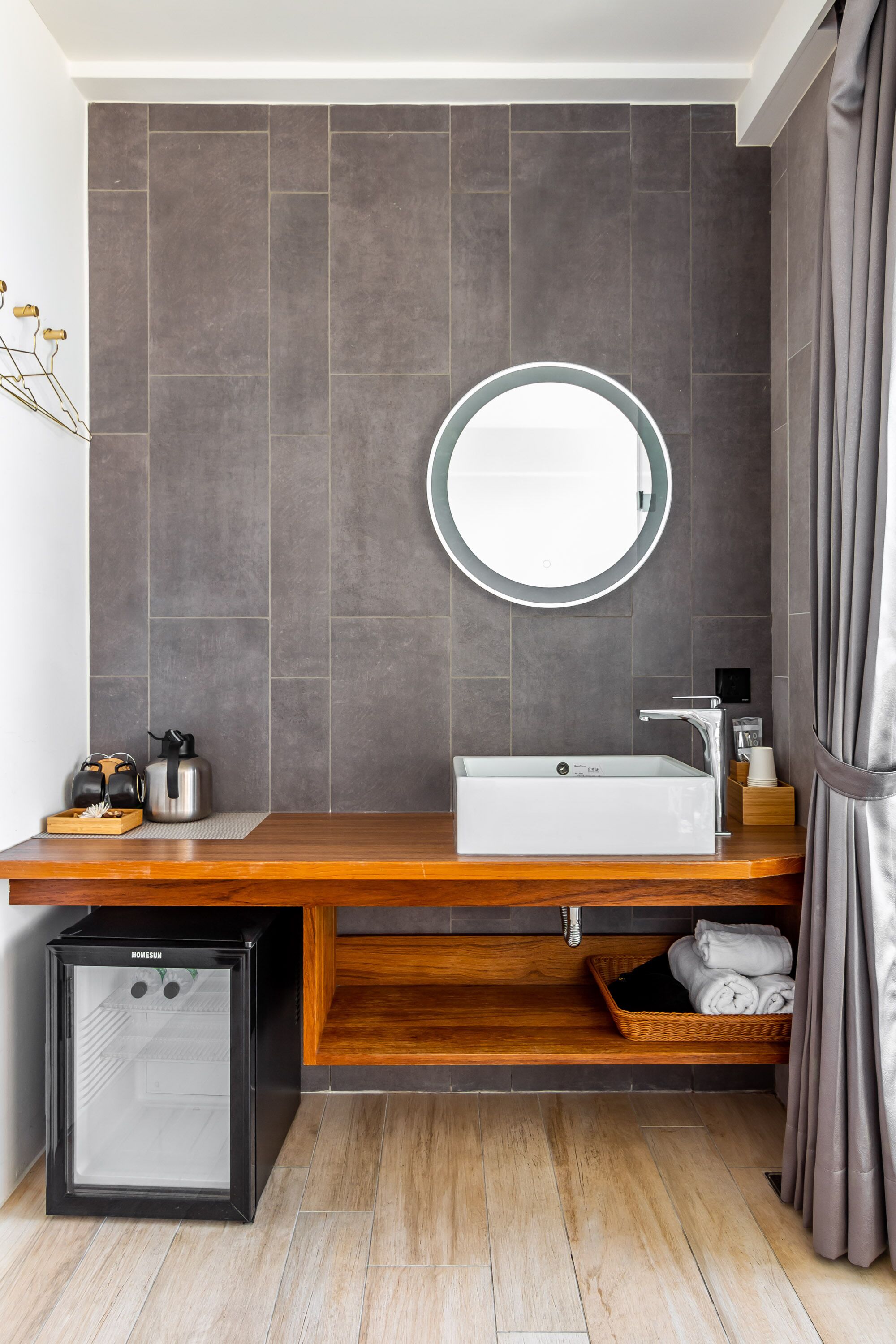 A modern bathroom with a wooden vanity, a sink, a mirror, and a built-in heater.