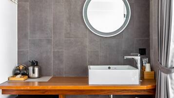 A modern bathroom with a wooden vanity, a sink, a mirror, and a built-in heater.