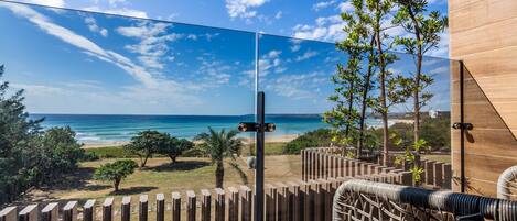 A balcony with a clear view of the beach and ocean.
