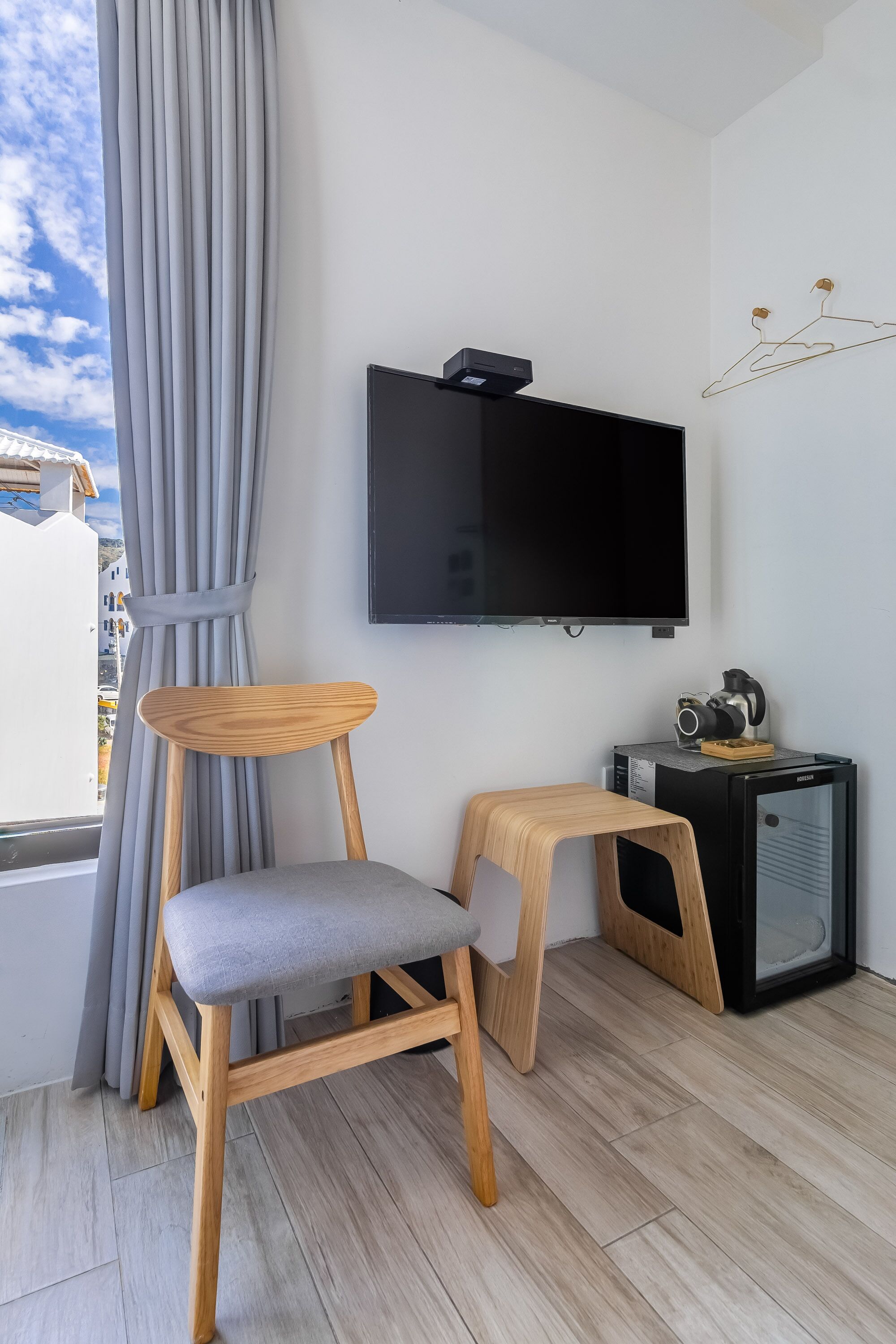 A modern living room with a wooden chair, a small table, a television, and a camera on a cabinet.
