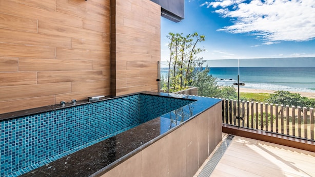 A modern outdoor pool with a wooden deck and a view of the ocean. - Kenting seawall Inn 112 (Hengchun)