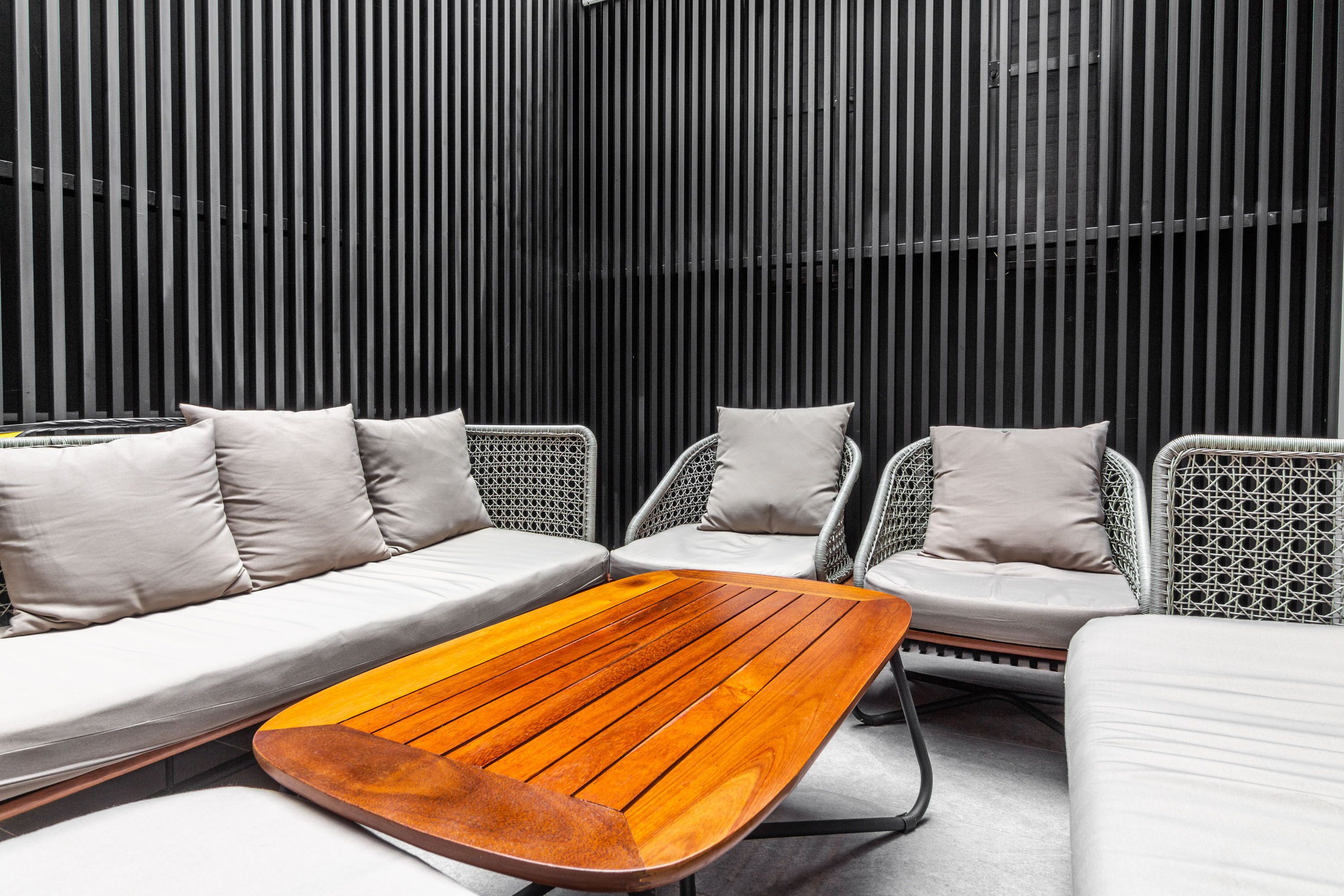 A modern outdoor seating area with a wooden table and white cushioned chairs.