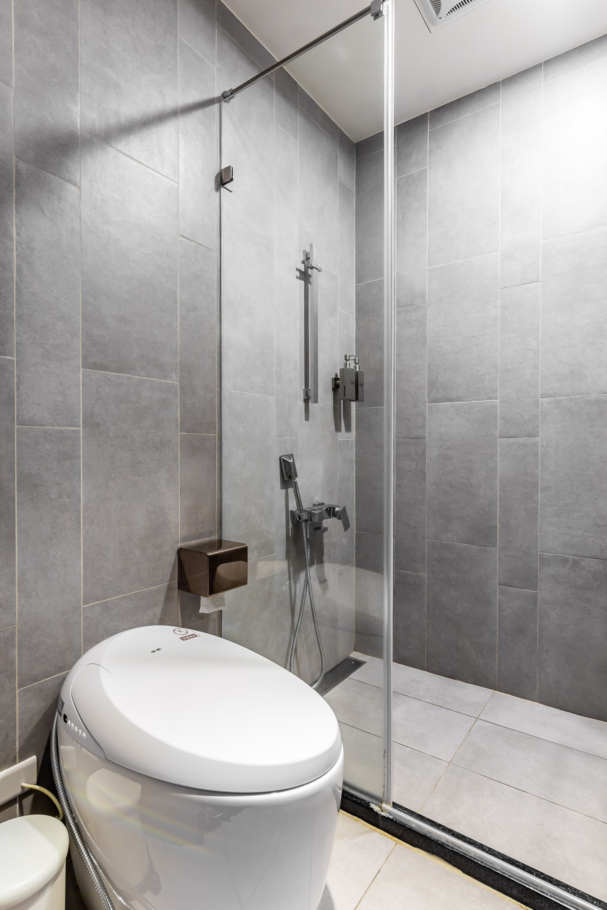 A modern bathroom with a glass-enclosed shower, a toilet, and a sink.