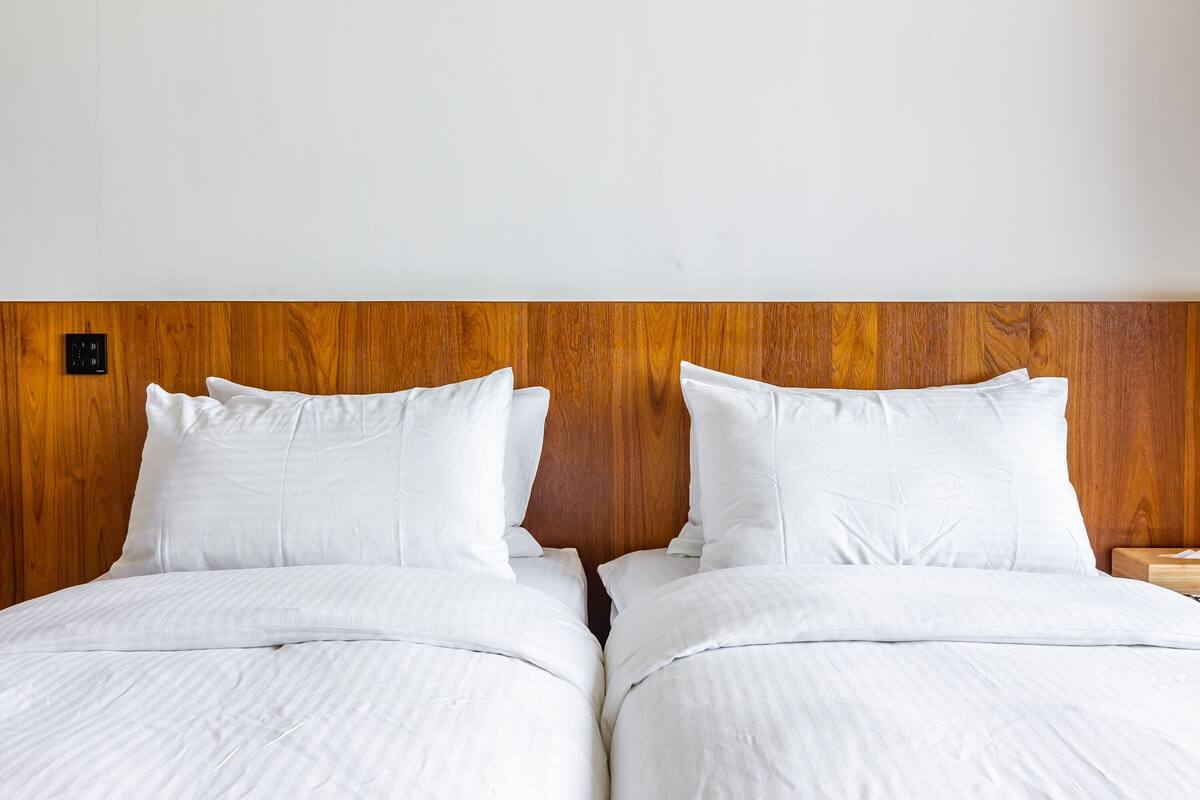 A double bed with white linens and a wooden headboard.