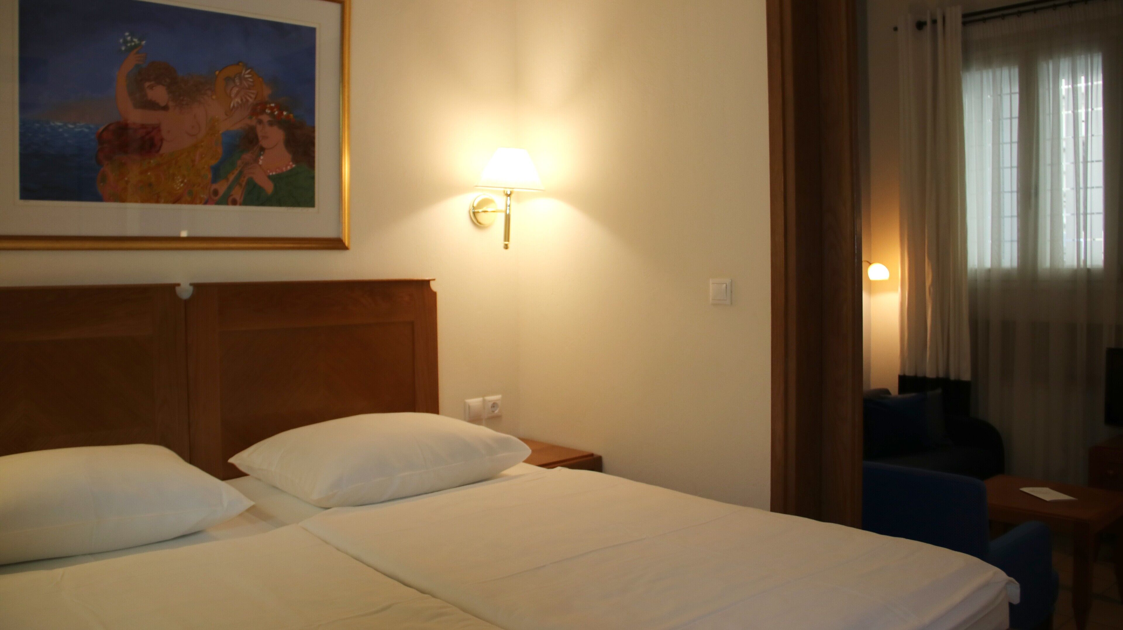 Une chambre d’hôtel avec un grand lit, une table de chevet, une lampe et un tableau au mur.