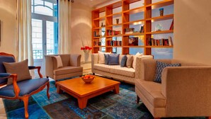 A living room with a sofa, chairs, a coffee table, and a bookshelf. - Hapimag Resort Athens (Athens)