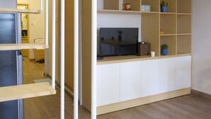 A modern living room with a built-in TV, wooden shelves, and a small potted plant. - 24h Saigon Hotel (Ho Chi Minh City)