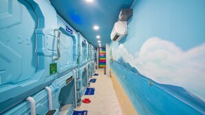 A row of blue, ocean-themed cabins with bunk beds, a mural of a beach scene, and a rainbow-colored wall in the background. - 24h Saigon Hotel (Ho Chi Minh City)