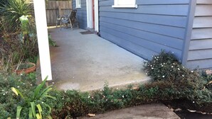 Un porche en béton avec un banc en bois et une plante en pot.
