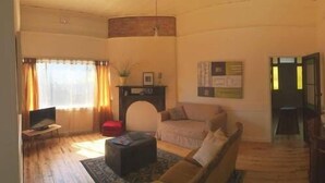 Un salon avec un canapé, un pouf et un téléviseur.
