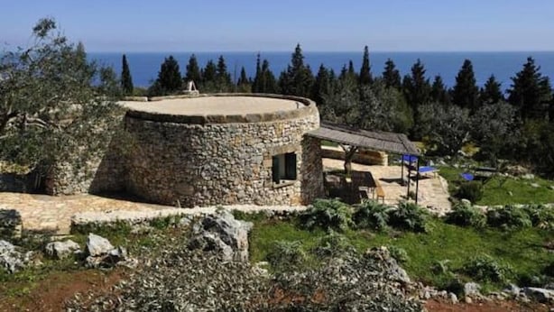 Edifici de pedra amb una estructura circular i un edifici més petit adossat amb teulada.