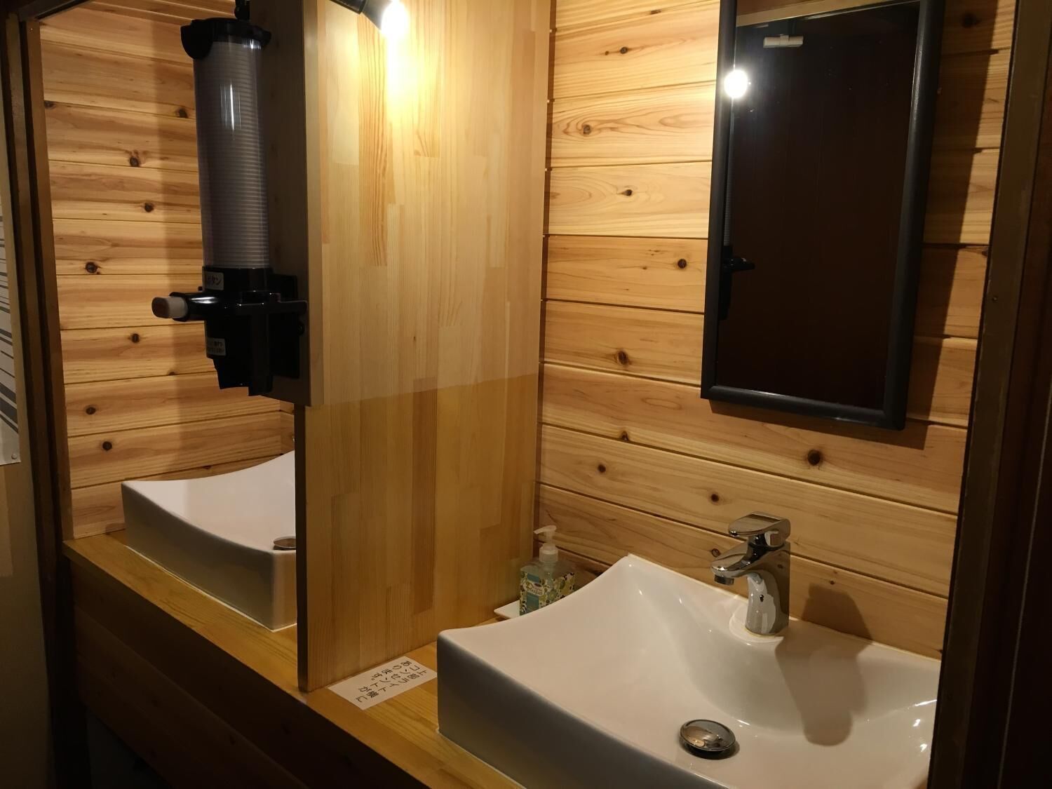 A wooden-paneled bathroom with two sinks and a mirror.