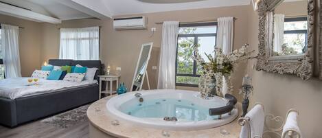 Un dormitorio moderno con una cama grande, un jacuzzi y un espejo amplio.