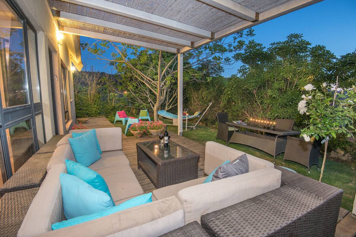 An outdoor patio with wicker furniture, a glass-top table, and a hammock.