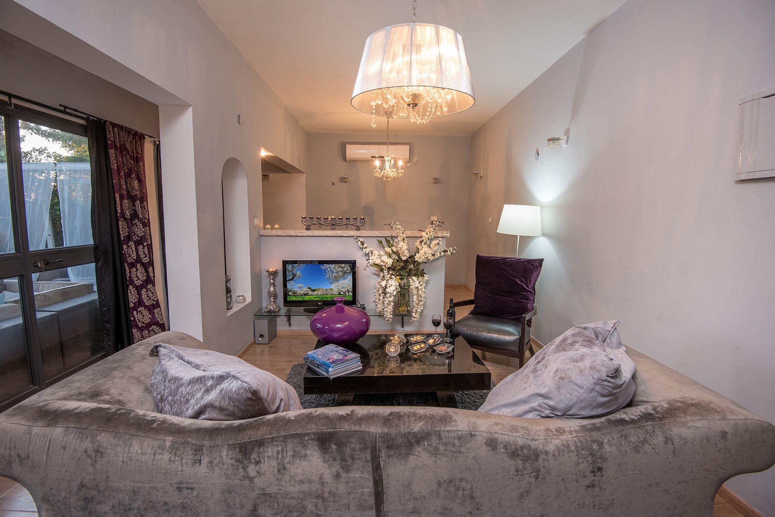 Ein Wohnzimmer mit einer Couch, einem Couchtisch, einem Fernseher und einer Chandel.