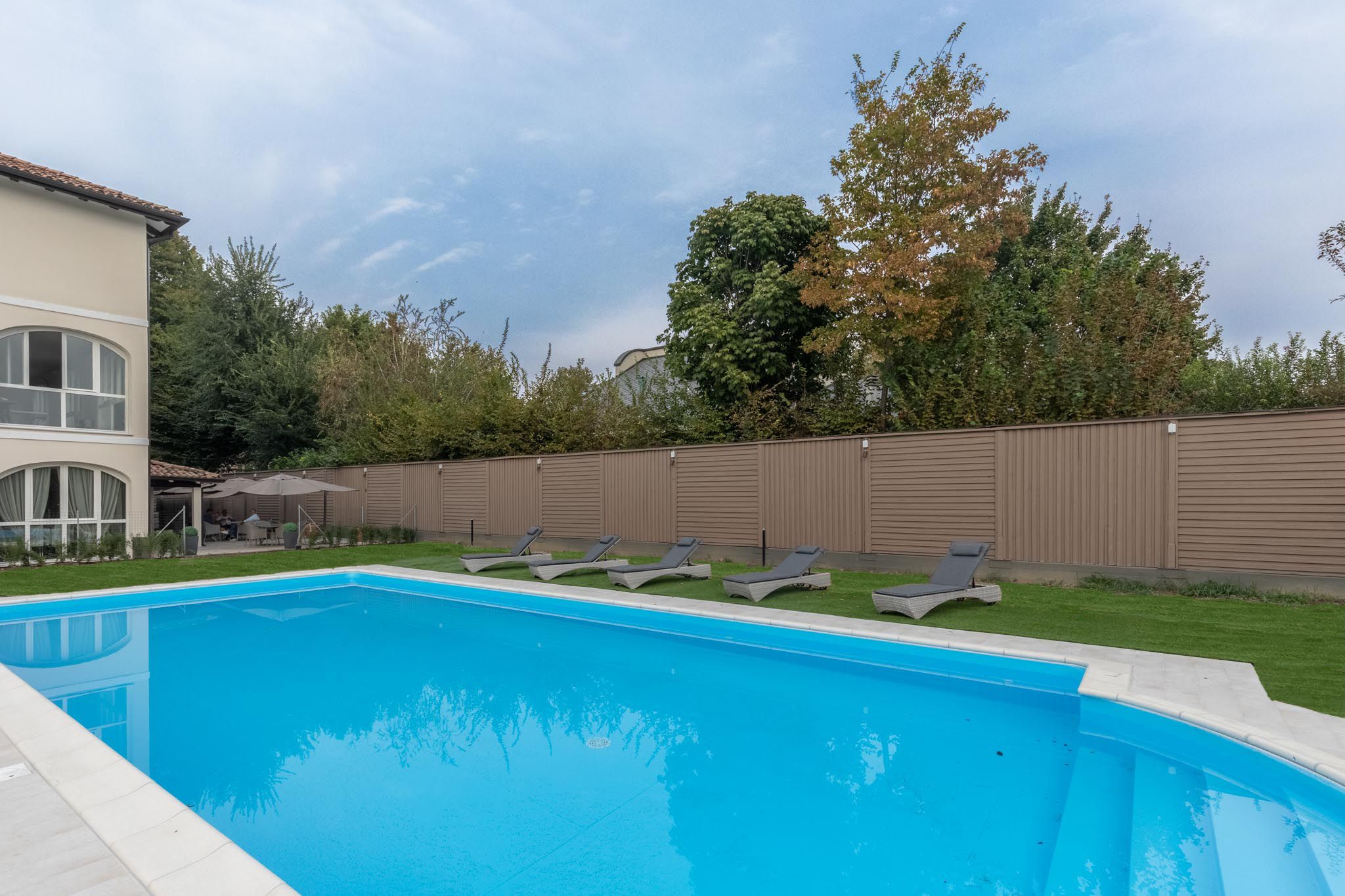Une piscine avec des chaises longues et un espace patio couvert.