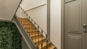 A staircase with wooden steps and a metal railing, leading to a door with a textured surface. - LxWay Apartments Travessa da Peixeira (Lisbon)