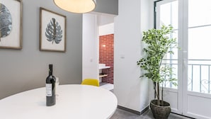 A dining area with a table, a bottle of wine, framed leaves on the wall, and a potted plant. - LxWay Apartments Travessa da Peixeira (Lisbon)
