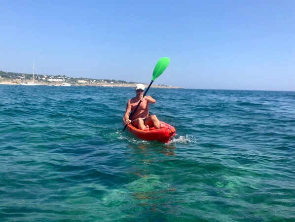 Una persona en kayak sobre el agua, con una vista despejada de la costa al fondo.