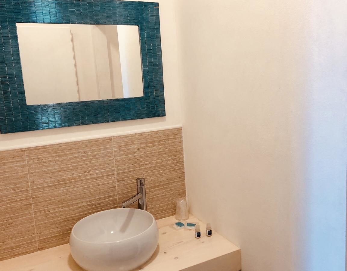 A bathroom with a white sink, a mirror, and a tiled backsplash.