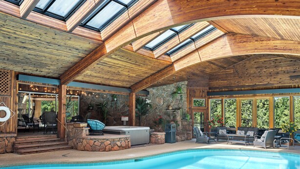 A pool area with a hot tub, lounge chairs, and a stone wall. - Panorama - Your Private Resort by Estes Park Homes (Estes Park)