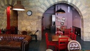 A cozy restaurant with stone walls, red and brown leather furniture, and purple accents. - Halex Room & Food (Nettuno)