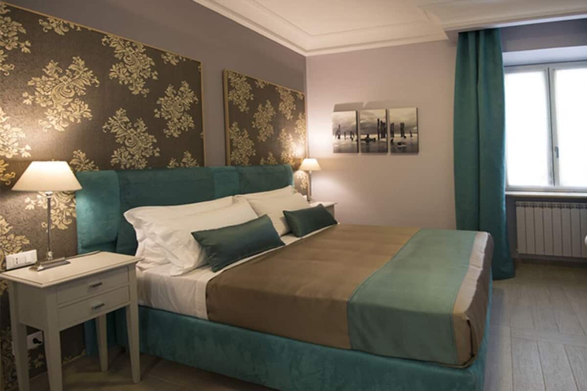 Une chambre d’hôtel avec un grand lit, un bureau, une chaise et une fenêtre avec des rideaux.