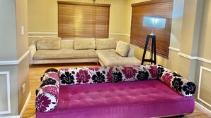 A living room with a sectional sofa, a chaise lounge, a chandelier, and a floor lamp. - Beautiful Apartment in Century City (Cape Town)
