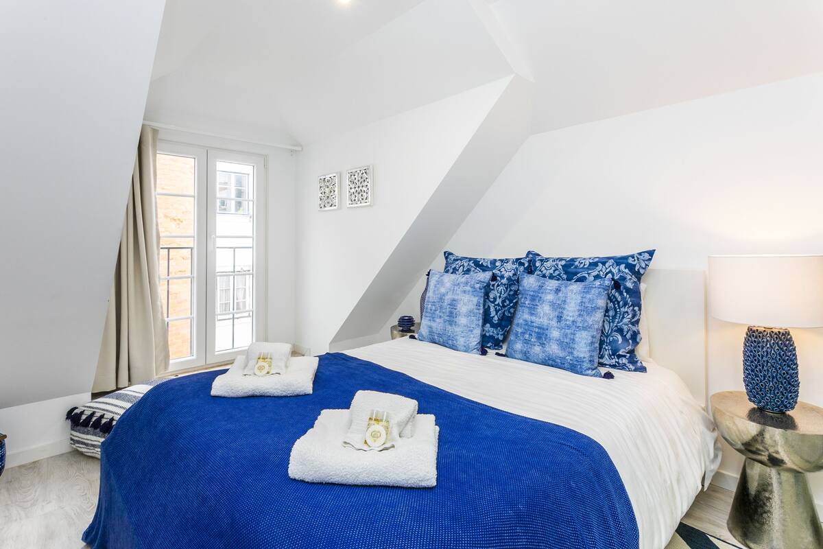 Een slaapkamer met een groot bed, twee nachtkastjes, een raam en een lamp.