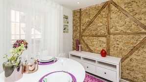 A dining area with a stone wall, white furniture, and a vase with flowers. - LxWay Apartments Old Town (Lisbon)