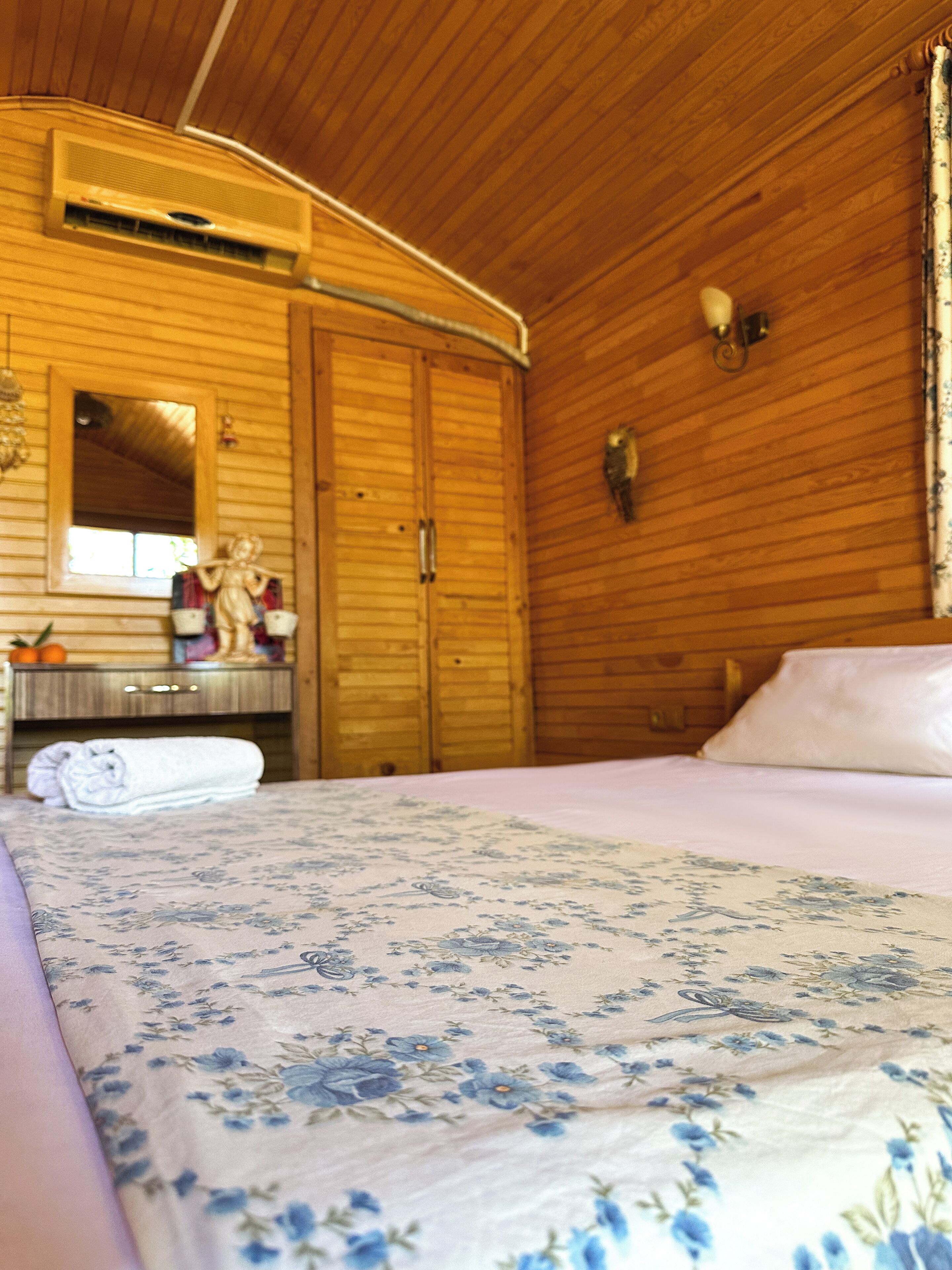 Una habitación de cabaña de madera con una cama, un tocador, un espejo y una ventana.