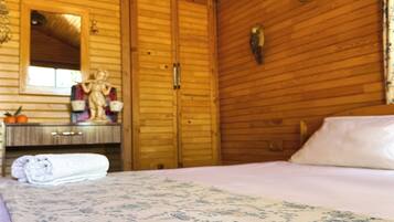 Una habitación de cabaña de madera con una cama, un tocador, un espejo y una ventana.