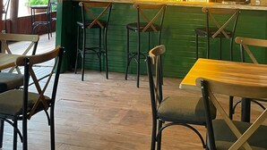 Un interior rústico de madera con barra, vigas de madera en el techo y una pared verde.