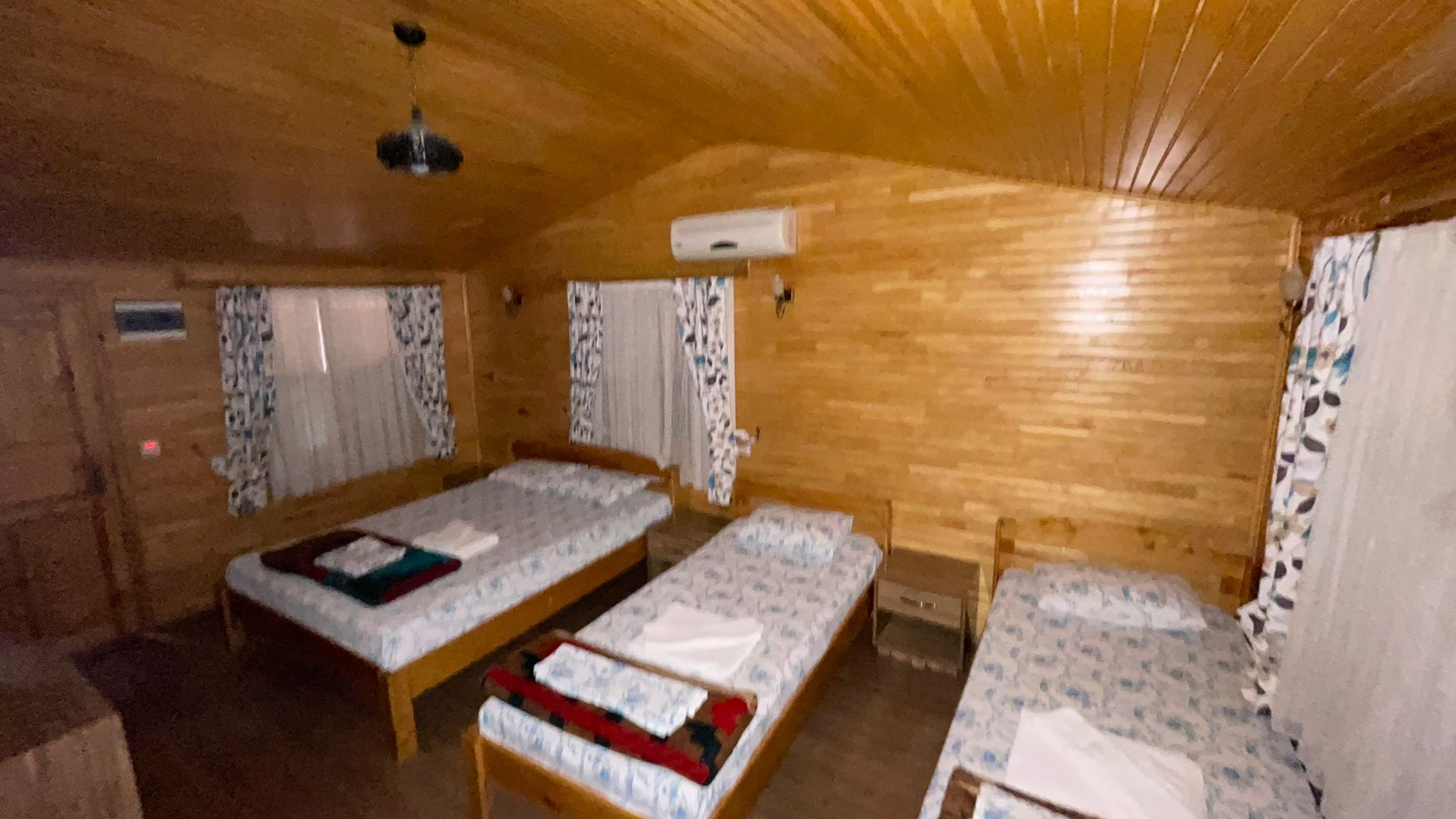 Una cabana amb dos llits de fusta, una taula petita i un ventilador de sostre.