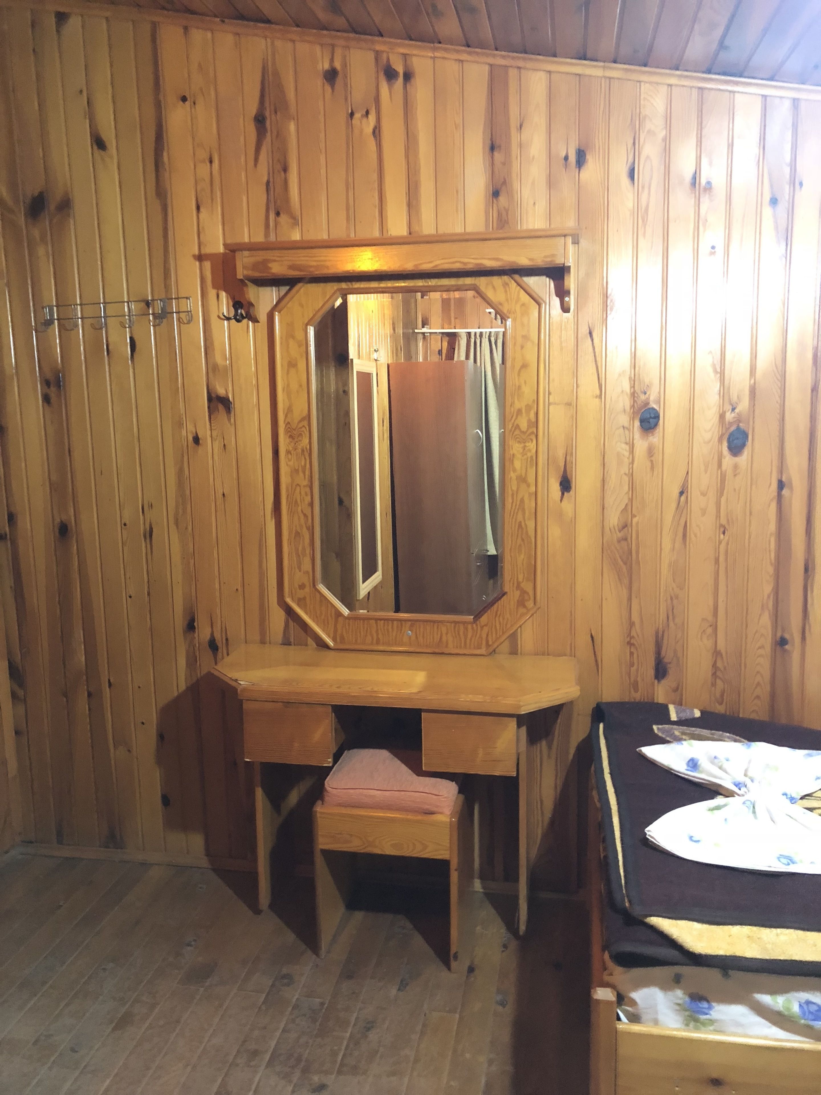 A wooden room with a vanity, a mirror, and a bench.