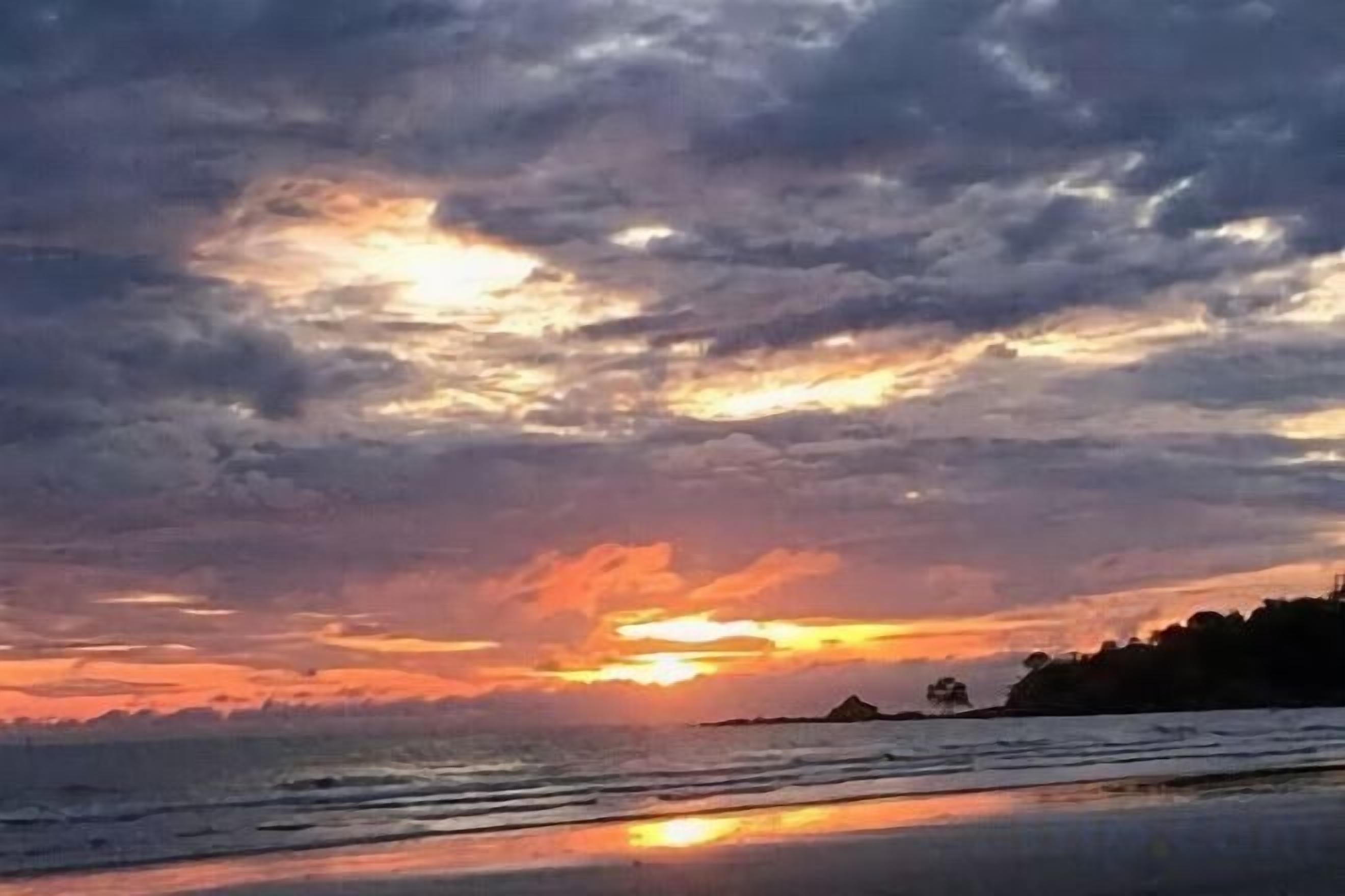 Una playa con un atardecer y nubes.