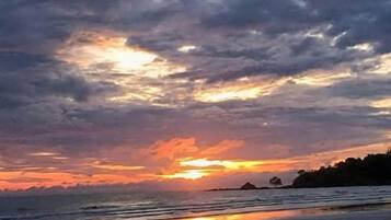 Una playa con un atardecer y nubes.