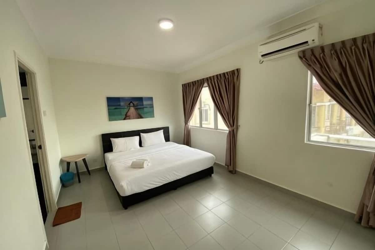 Een slaapkamer met een bed, een raam met gordijnen, een schilderij aan de muur en een airconditioning.