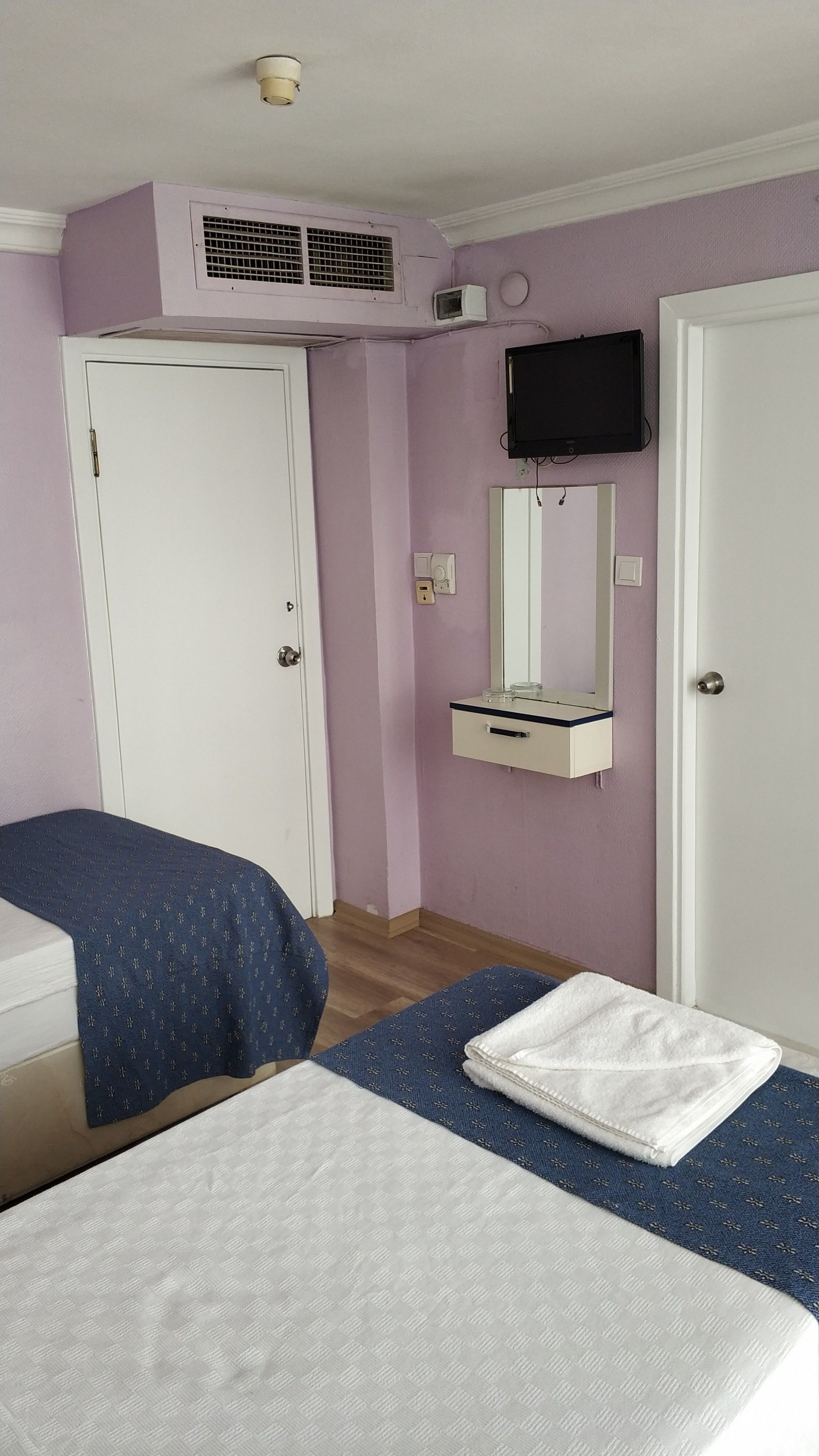Une chambre d’hôtel comprenant un lit, une table de chevet, un miroir, une télévision et une armoire.