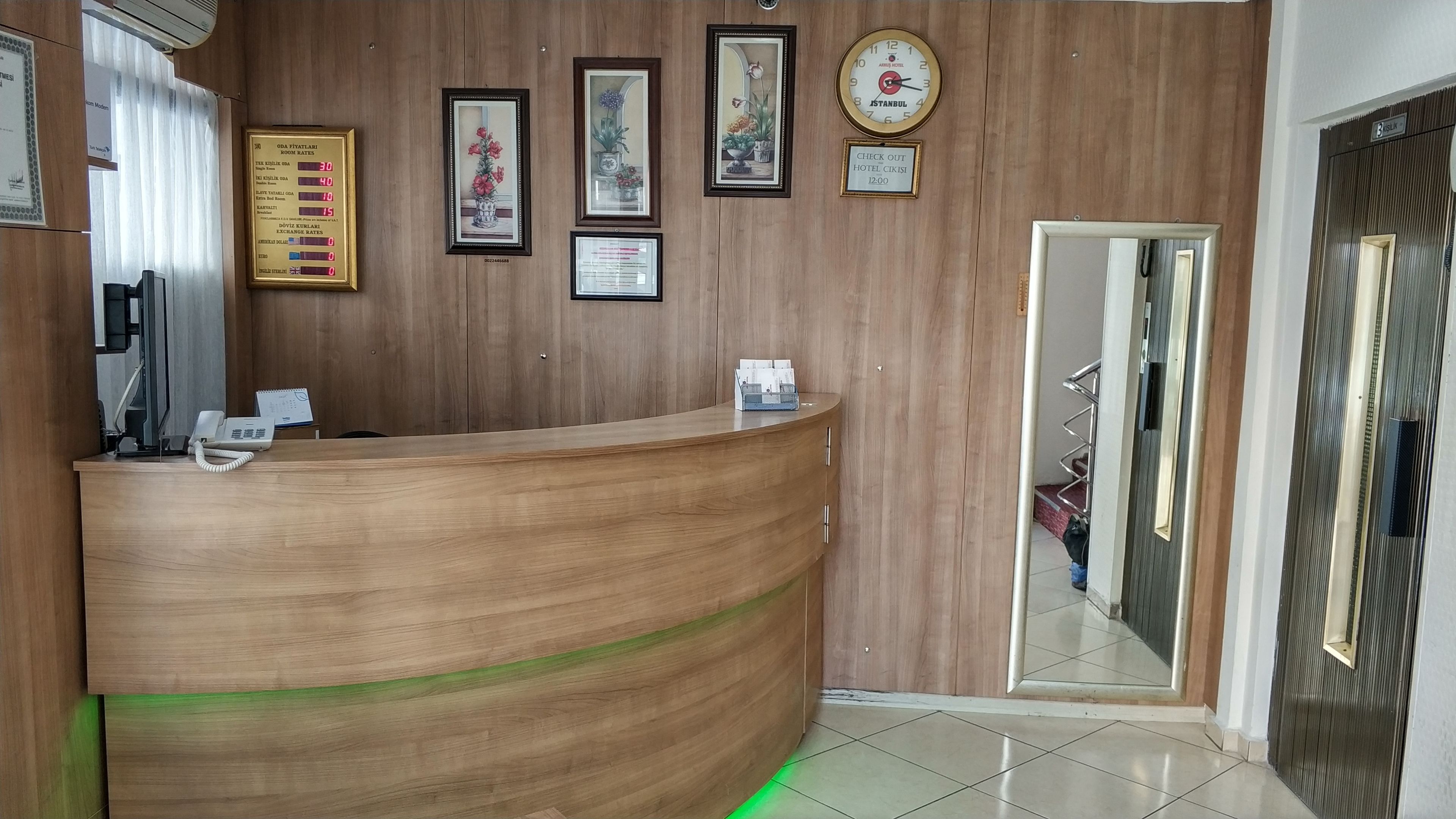 A reception desk with a wooden finish, a clock, framed artwork, and a check-out sign.