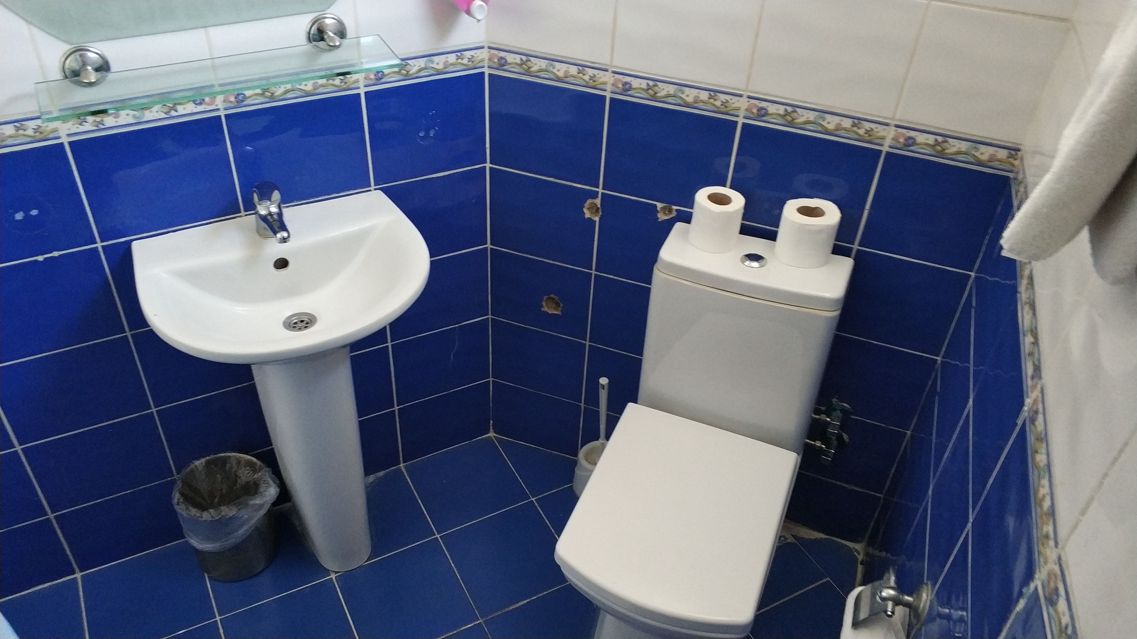 A bathroom with a white sink, toilet, and blue tiled walls.