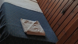 A bed with a blue and white patterned bedspread, a white pillow, and a folded towel on the bed. There is a remote control on the wall to the right of the bed. - Akkus Hotel (Istanbul)