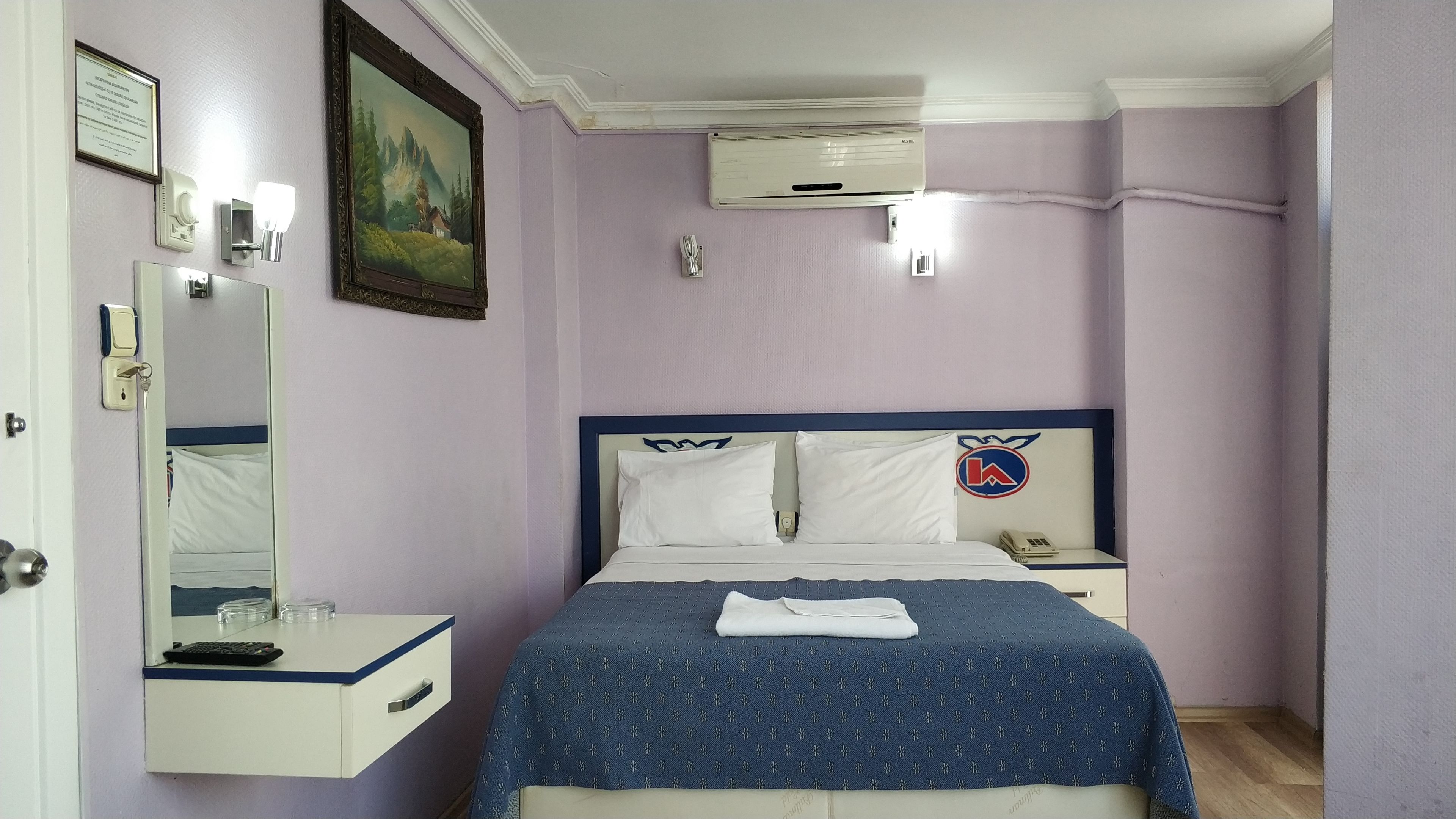Ein Schlafzimmer mit einem Bett, einem Nachttisch, einem Spiegel und einer Wand-Klimaanlage.